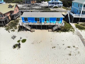 A beachfront house with a blue exterior, wooden deck, and a small porch. - Beachfront & Dog Friendly! (Gulf Shores)