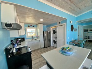 A compact kitchen with a sink, microwave, and a double-door washer-dryer unit. - Beachfront & Dog Friendly! (Gulf Shores)