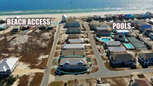 Vue aérienne d’un quartier résidentiel situé sur la côte, avec accès à la plage et présence de piscines.