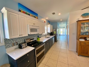 A modern kitchen with white cabinets, a microwave, a stove, and a coffee maker.