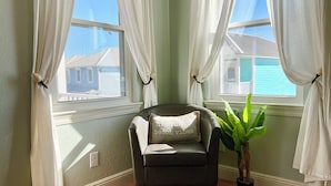 A corner room with a chair, a potted plant, and a window with curtains. - Great Views & Pools! Easy Beach Access (Gulf Shores)
