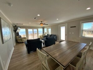 Un salon spacieux avec une grande table à manger en bois, deux canapés et un ventilateur de plafond.