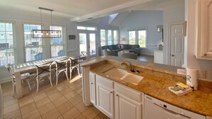 A modern kitchen with white cabinetry, a granite countertop, and a built-in dishwasher. - Great Gulf Views & Pools, Pickleball (Gulf Shores)