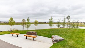 A park with a bench and a stone feature by a lake. - Deluxe Suite w/Fast WiFi, Perfect for Long Stays (Airdrie)