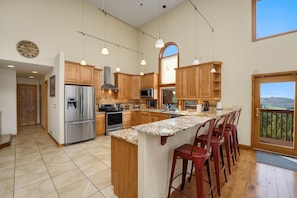 A spacious kitchen with wooden cabinets, stainless steel appliances, and a large island with bar stools. - Colorado Mountain Retreat with Unbeatable Views! (Livermore)