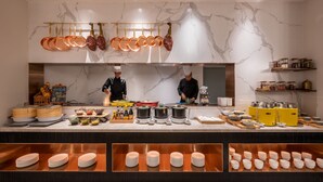 Une cuisine aux murs de marbre, avec des ustensiles de cuisine en cuivre et des chefs qui préparent les plats.