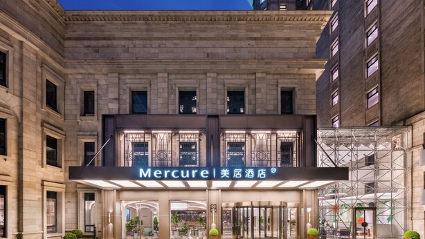 L’entrée d’un hôtel, avec une enseigne indiquant « Mercure » et une façade moderne.