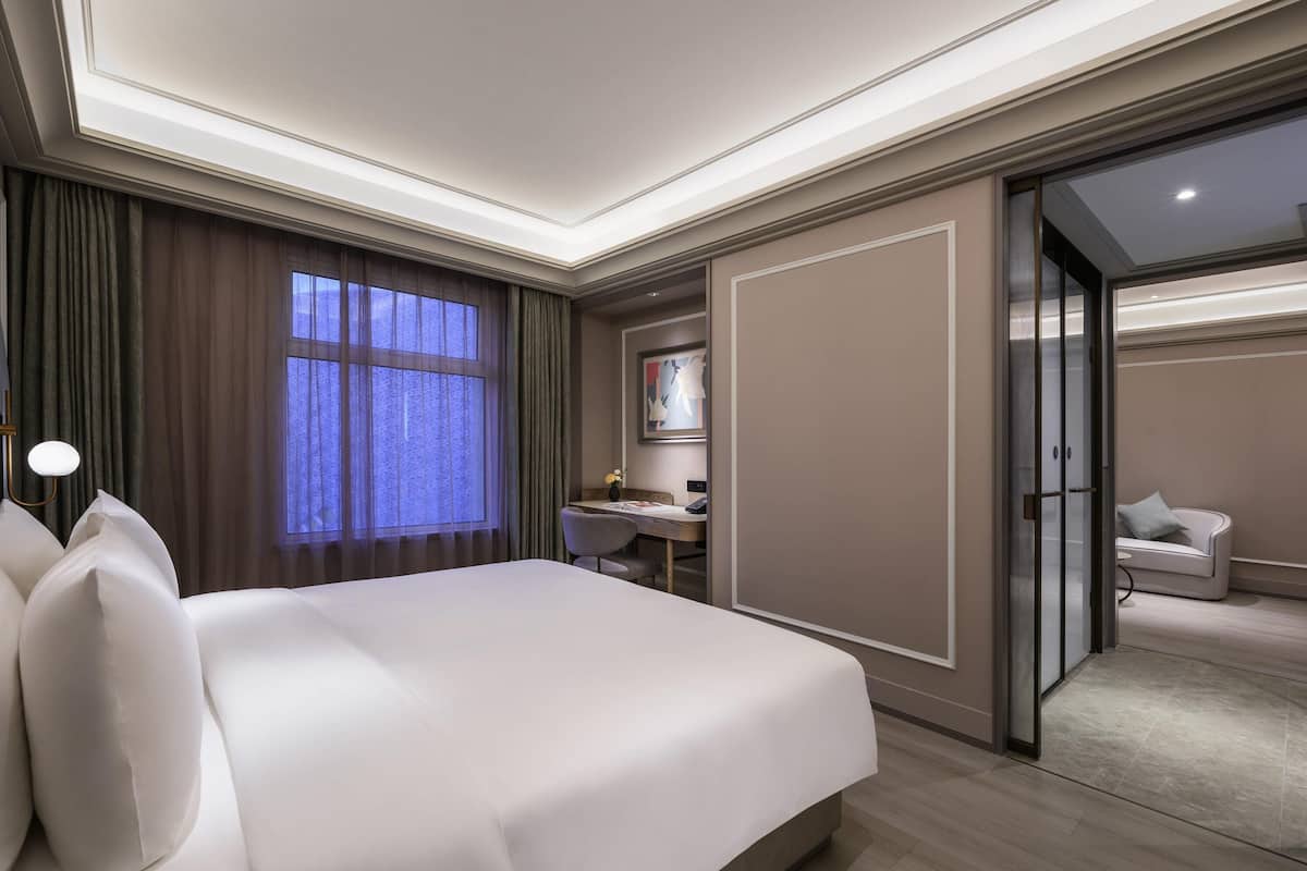 Camera d'albergo con un letto grande, una scrivania, una sedia e una porta scorrevole che dà su un balcone.