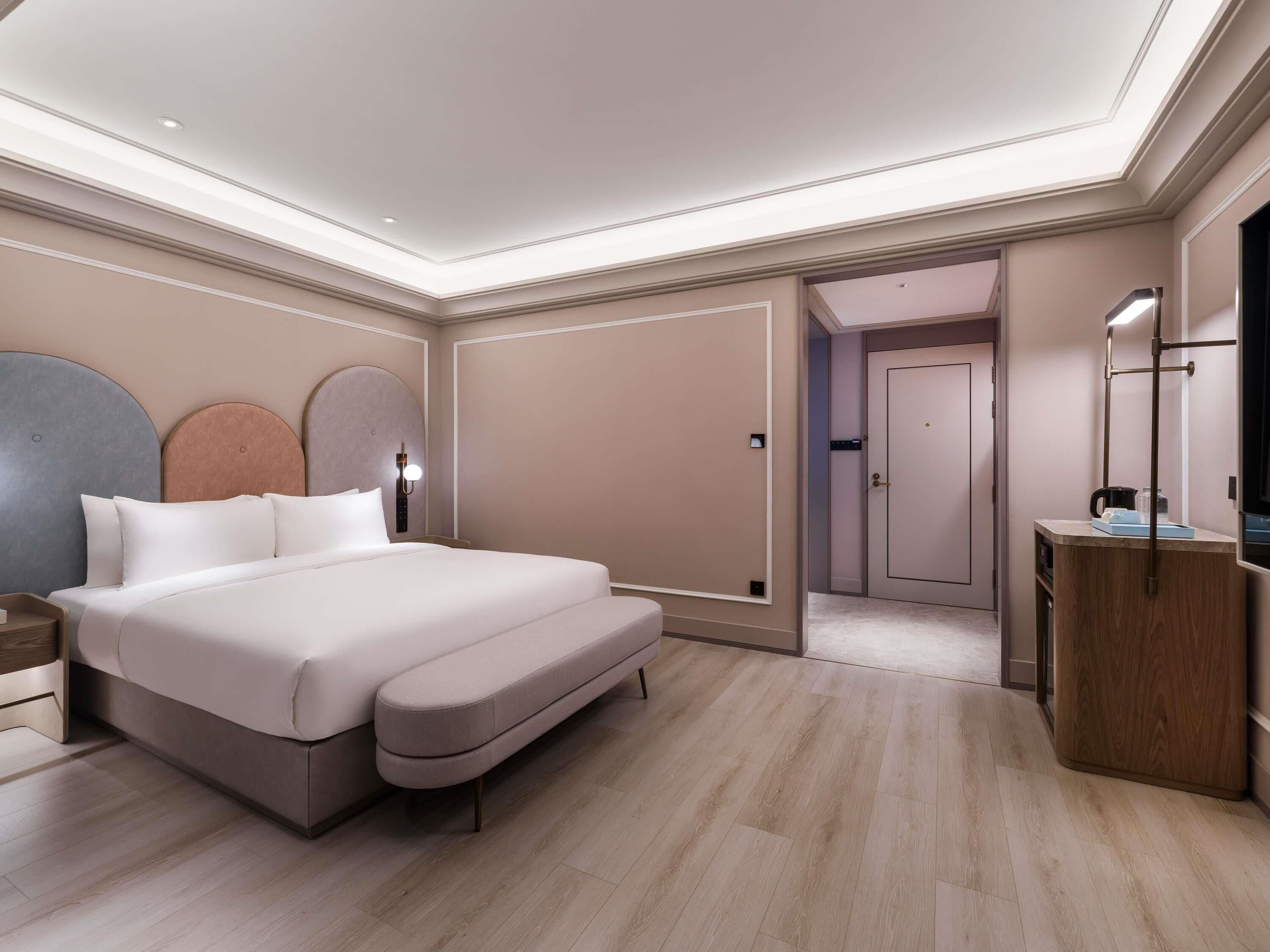 Quarto moderno com cama grande, mesas de cabeceira, guarda-roupa e espelho.