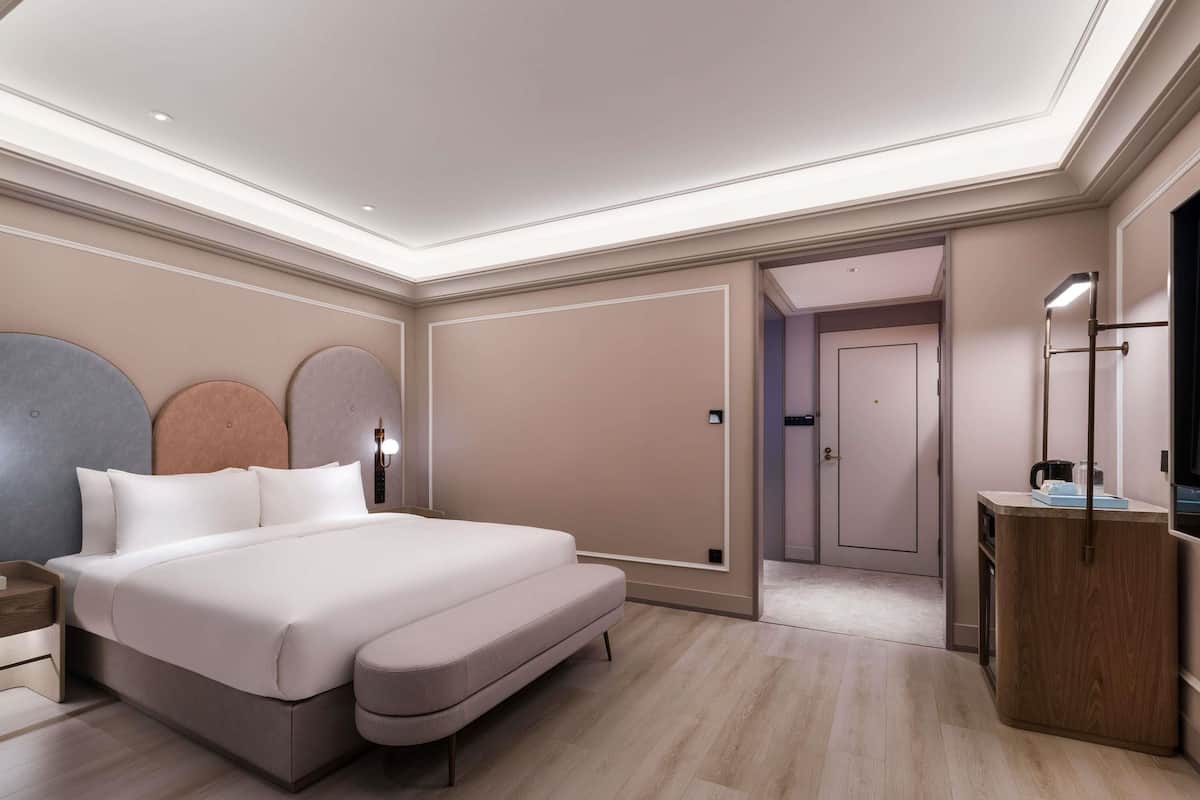 Quarto moderno com cama grande, mesas de cabeceira, guarda-roupa e espelho.