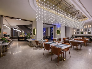 Un restaurant moderne avec un espace de restauration central, un bar et un escalier menant à un niveau supérieur.