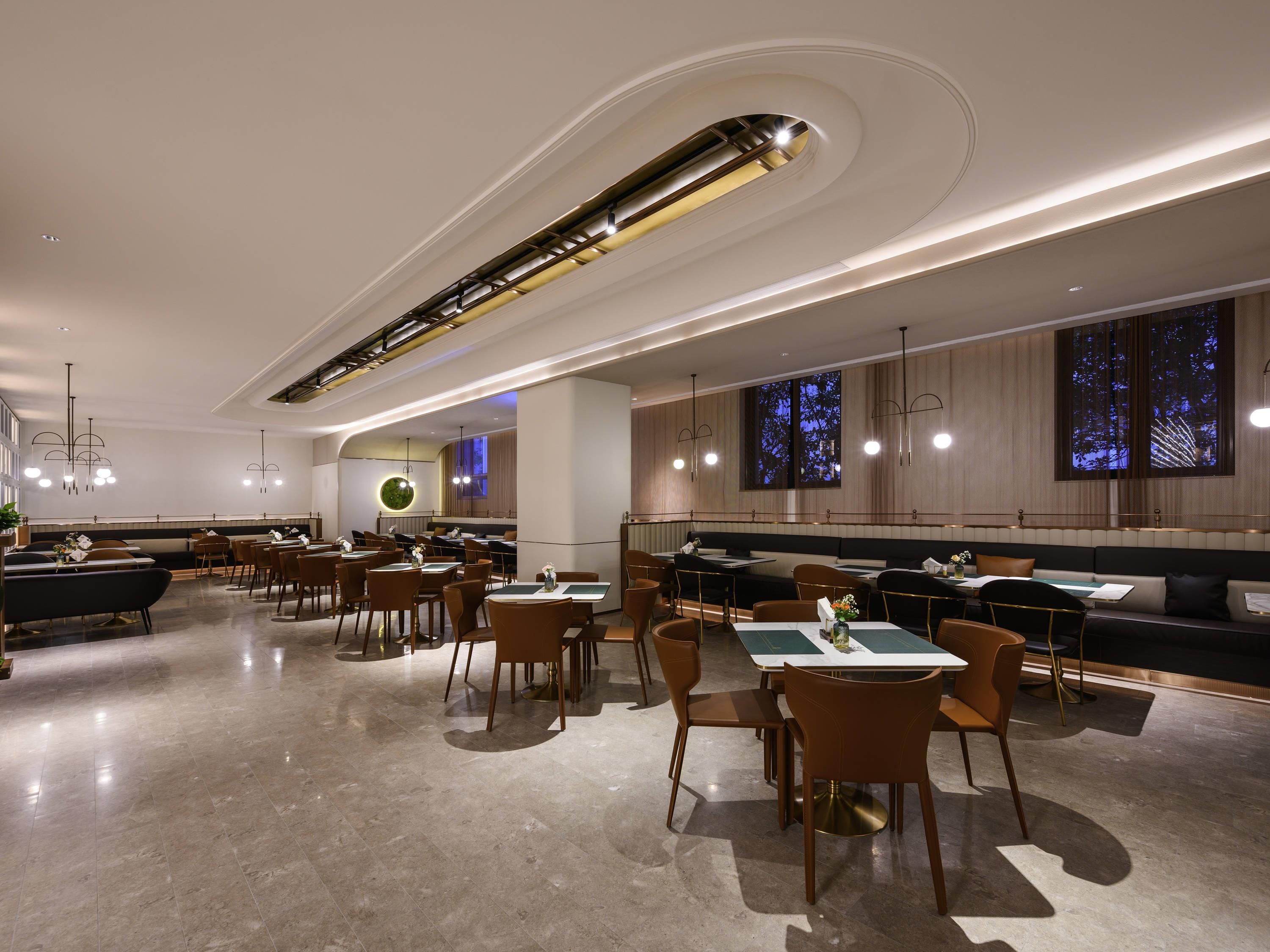 A modern restaurant with a long counter, multiple tables, and chairs.