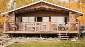 A cabin with a wooden deck, a covered porch, and a chimney.