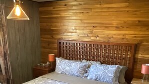 A wooden-paneled bedroom with a bed, nightstands, and a desk.