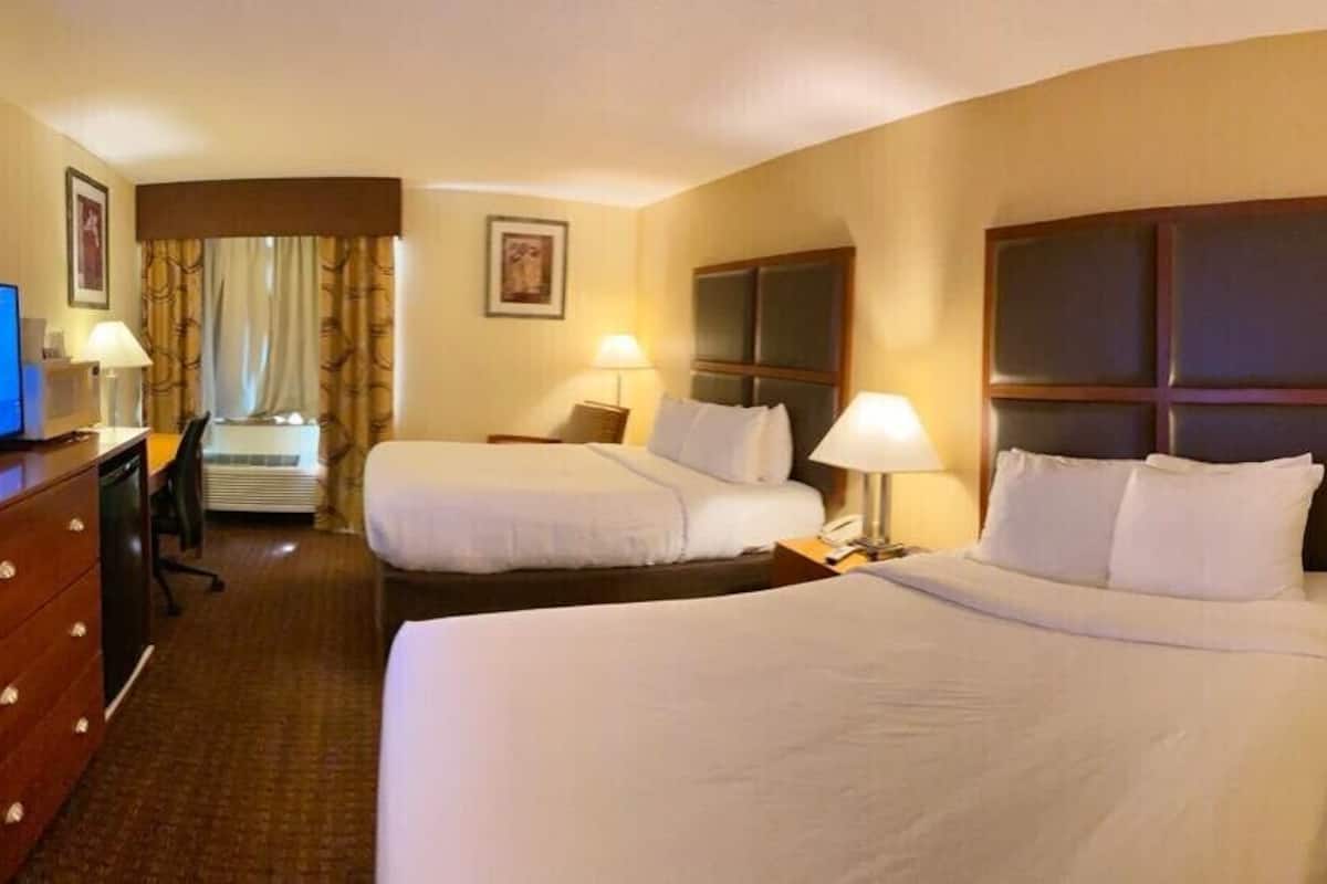 A hotel room with two beds, a desk with a computer, and a TV.