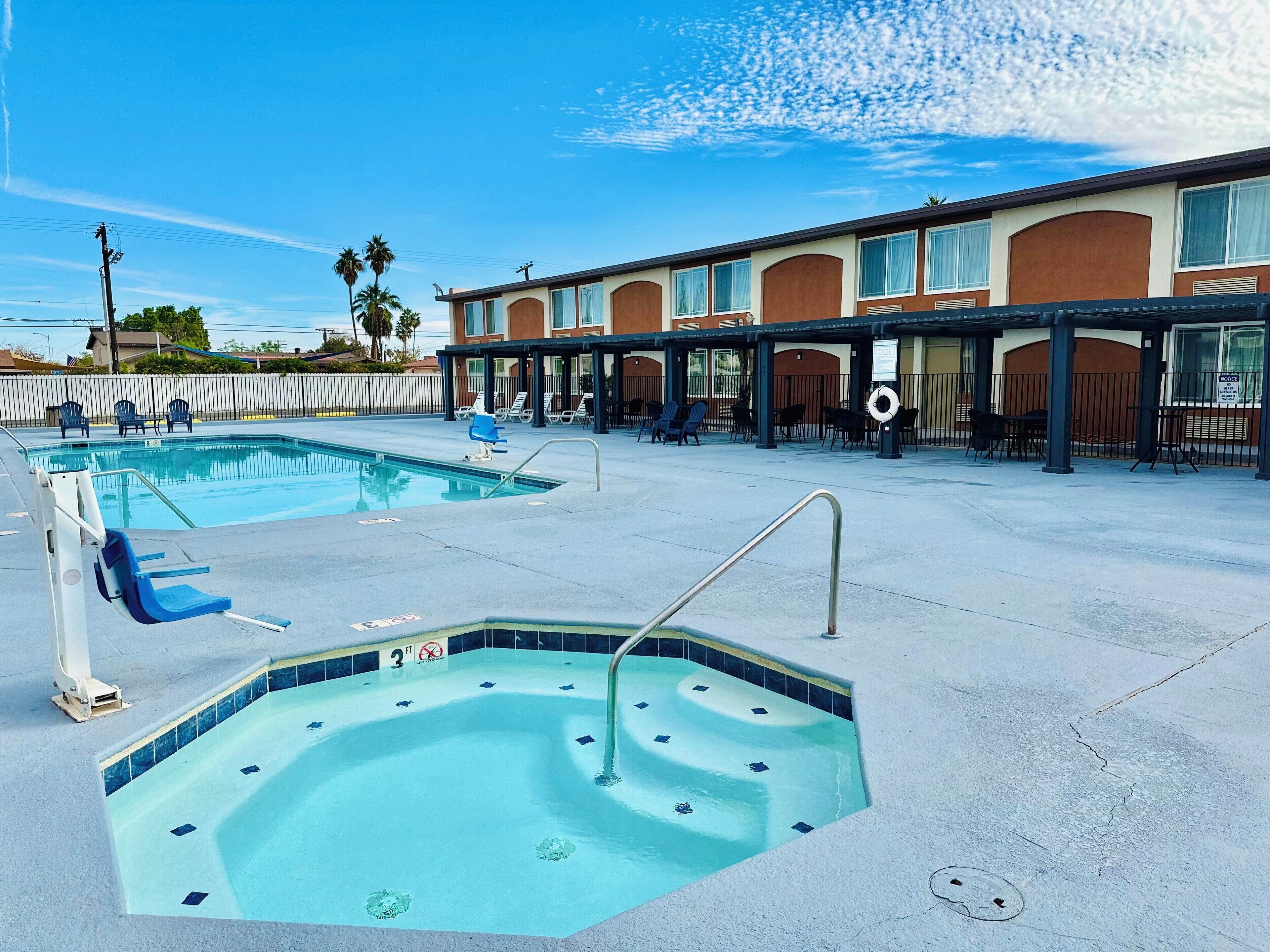 A hotel with a swimming pool, outdoor seating, and a covered area.