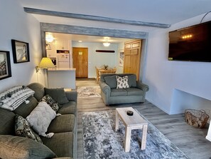 Un salon avec un canapé, une table basse et un téléviseur fixé au mur.