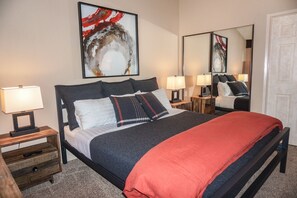 Une chambre à coucher bien rangée, avec un grand lit, deux tables de chevet et un miroir.