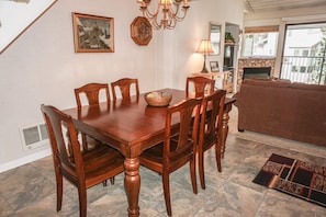 A dining area with a wooden table and chairs, a fireplace, and a view of the outdoors.
