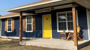 A two-story building with a dark blue exterior and a yellow front door. There is a sign above the door that reads "Patricia's Cottage."