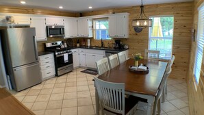 A modern kitchen with white cabinets, stainless steel appliances, and a dining area with a wooden table and chairs.
