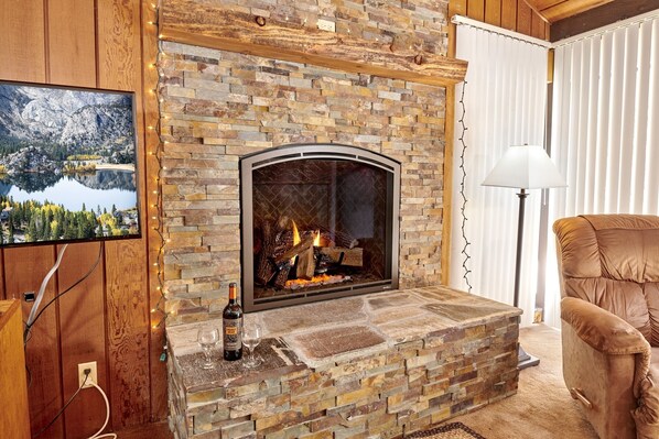 A stone fireplace with a TV mounted above it, a chair, and a lamp.