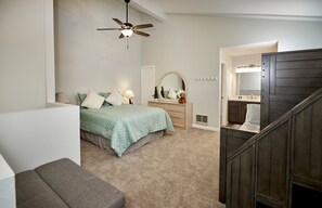 Une chambre à coucher avec un lit, une commode, un miroir et un ventilateur de plafond.