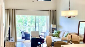 Een ruime woonkamer met balkon, een eettafel en een bank.
