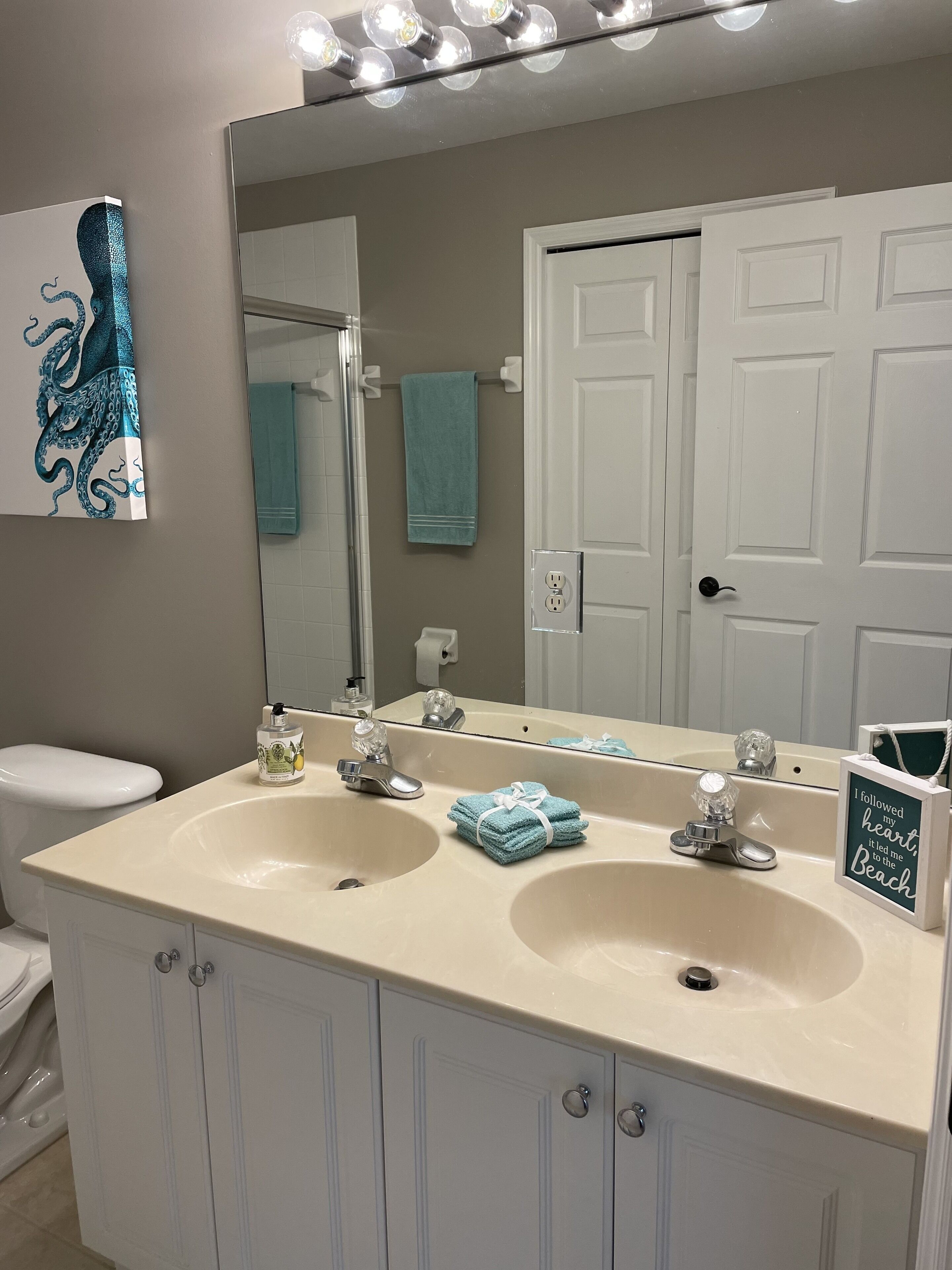 A bathroom with two sinks, a large mirror, and a towel rack.