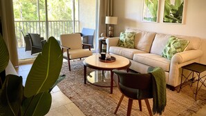 Een woonkamer met een bank, twee fauteuils, een salontafel en een balkon met stoelen.
