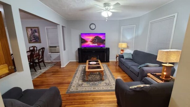Ein Wohnzimmer mit Flachbildfernseher, einer Couch, einem Couchtisch und einem Kamin.