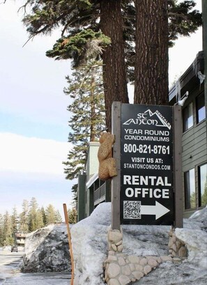 A rental office sign for Stanton Condominiums with contact information and a QR code.