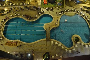 A large outdoor swimming pool with multiple lanes, surrounded by lounge chairs and a seating area.