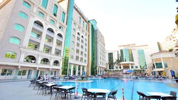 A hotel with a pool area, outdoor seating, and a modern architectural design.