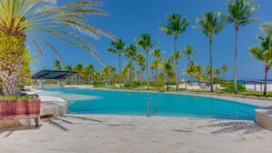 Area piscina con palme, una poltrona da relax e una zona salotto coperta.