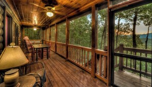 A wooden deck with a table and chairs, large windows, and a ceiling fan. - Red Roof Zen Where Adventure Meets Mountain Views (Blue Ridge)