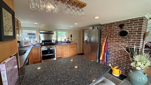 Eine moderne Küche mit Granit Arbeitsplatten, Edelstahlgeräten und einer Wand mit Ziegeln.