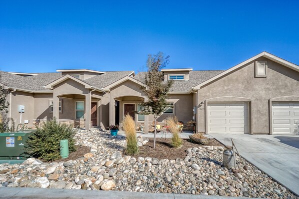 A residential house with a garage, a driveway, and a landscaped front yard with rocks and plants.