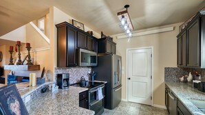 A modern kitchen with dark cabinets, stainless steel appliances, and a granite countertop. - Beautiful Town Home in Poncha Springs- minutes to Monarch Mountain (Poncha Springs)