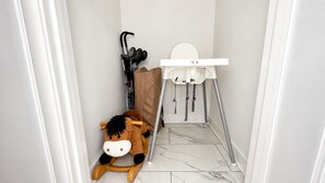 Un couloir étroit avec un espace pour changer les bébés, une poussette et un cheval à bascule.