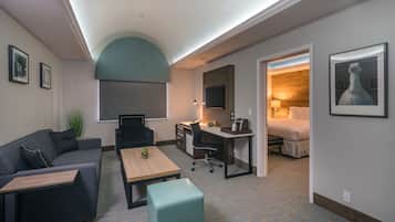 A modern hotel room with a sofa, desk, and a bed.