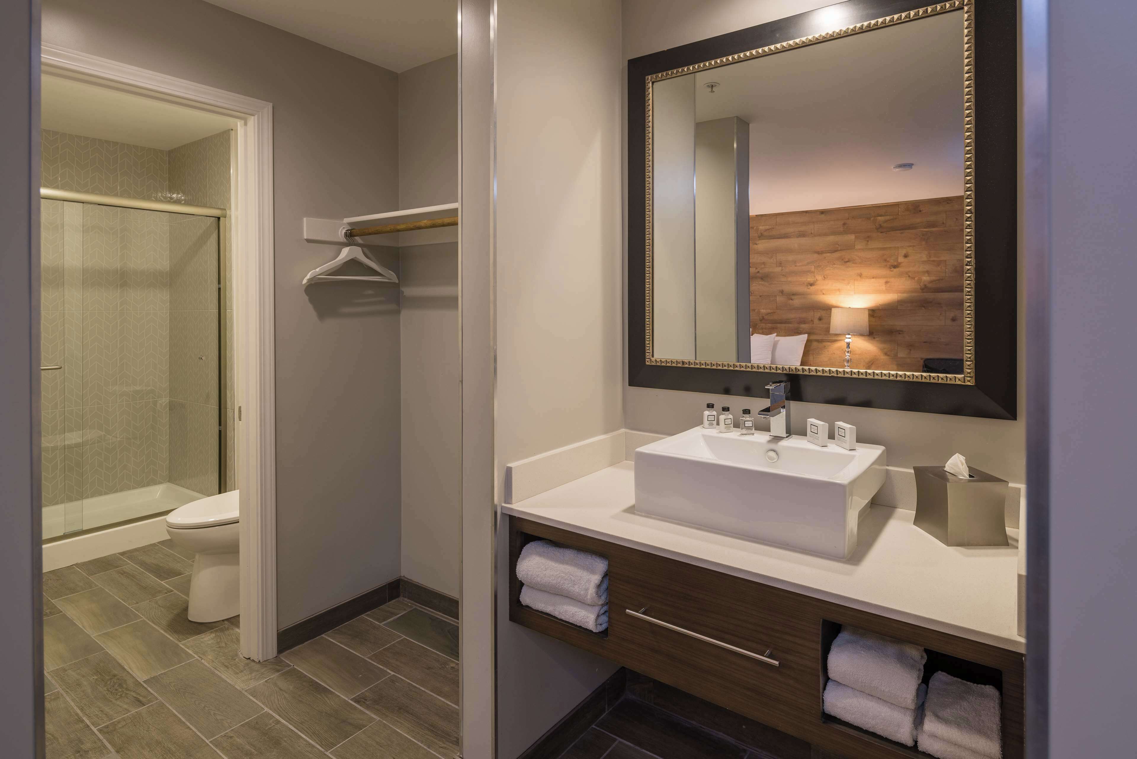 A modern bathroom with a walk-in shower, a vanity with a large mirror, and a built-in towel rack.