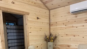 Una camera in legno con due sedie a righe, un tavolino e un vaso con fiori.