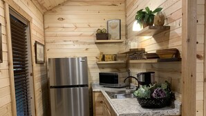 Una cucina compatta con pareti in legno, un frigorifero in acciaio inossidabile, un forno a microonde e un lavello.