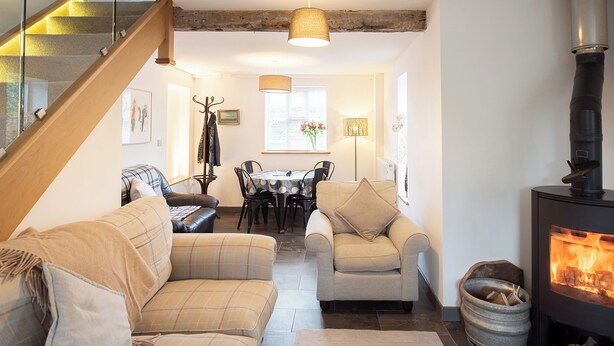 A cozy living room with a fireplace, a dining area, and a staircase. - 3 bedroom accommodation in Forden (Forden)