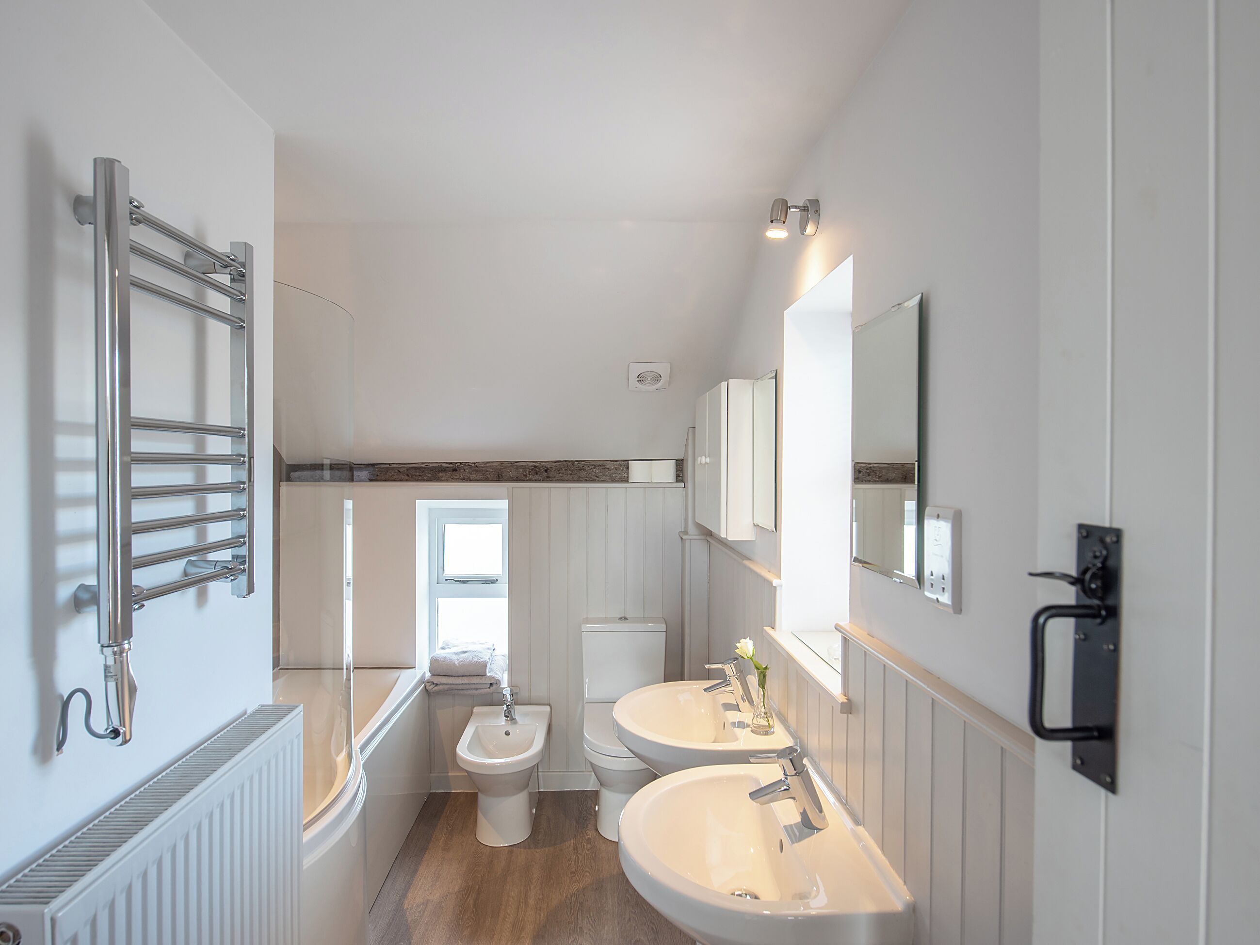Ein modernes Badezimmer mit zwei Waschbecken, einem Bidet und einem Handtuchhalter.