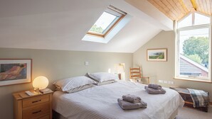 A bedroom with a skylight, a bed with pillows, a bedside table with a lamp, and a window with a view of greenery. - 3 bedroom accommodation in Forden (Forden)