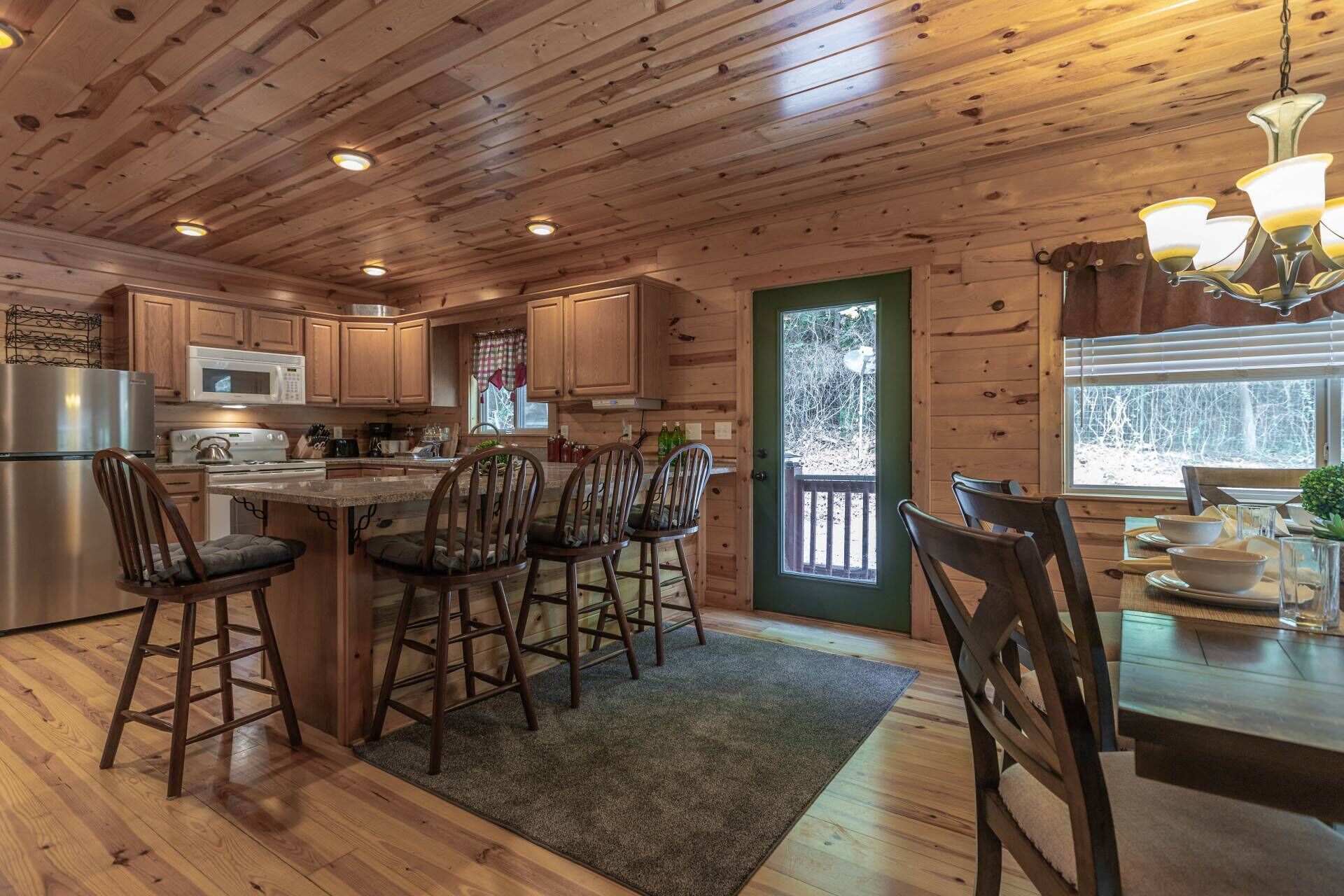L’intérieur d’un chalet en bois comprend une cuisine, un coin repas et une grande fenêtre.