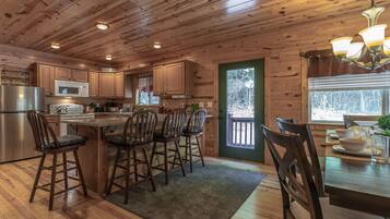 L’intérieur d’un chalet en bois comprend une cuisine, un coin repas et une grande fenêtre.