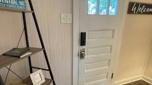 A room with a white door, a welcome sign, a wooden floor, and a blue patterned rug. - Cheerful 2-bedroom Edenton bungalow getaway (Edenton)